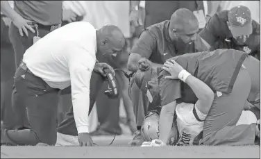  ?? Associated Press ?? Milton injured: South Florida coach Charlie Strong, left, comforts Central Florida quarterbac­k McKenzie Milton, who had injured his right leg during the first half of their game Friday in Tampa, Fla.