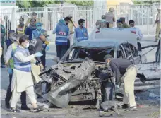  ?? — AFP ?? Security officials inspect a destroyed vehicle after an explosion in Lahore on Monday.