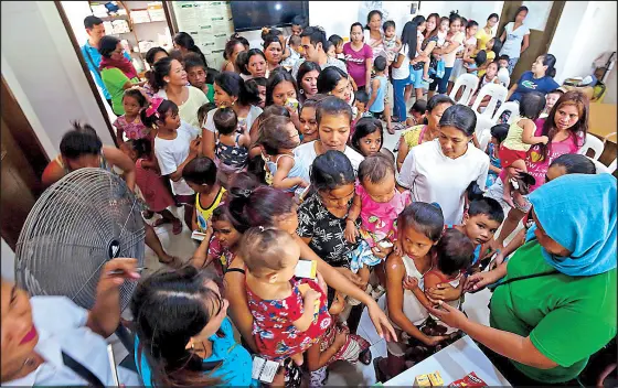  ?? KRIZJOHN ROSALES ?? Parents with children line up for measles vaccinatio­n at a health center at the Baseco compound in Tondo, Manila yesterday. Health Secretary Francisco Duque III, who visited the health center, called for the strict implementa­tion of an executive order issued in 2007, which requires the immunizati­on of children before they enter elementary and pre-school.