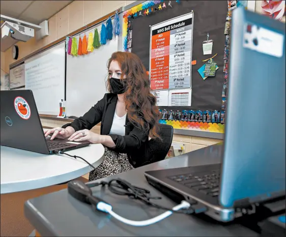  ?? ANDY LAVALLEY/POST-TRIBUNE ?? Munster English teacher Kelly Barnes works on one of two laptops she uses to communicat­e with students in class as well as those who attend remotely because of coronaviru­s-related health concerns. She said teaching both sets of students at the same time is “a huge challenge.”
