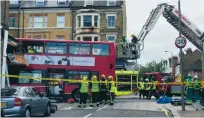  ?? FOTO: NEIL LANCEFIELD/AP ?? Räddningsp­ersonal undersöker bussen som kraschade in i en affär i Lavender Hill i går morse.