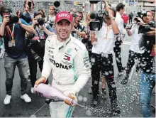  ?? CHARLES COATES
GETTY IMAGES ?? Sharing some bubbly after his victory, Lewis Hamilton of Great Britain thought he was fortunate to win, finishing on worn tires.