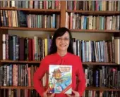  ?? PROVIDED BY AUTHOR ?? Jilin-born writer Songju Ma Daemicke holds a copy of her new book Cao Chung Weighs an Elephant.