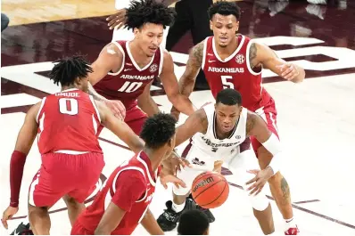  ?? AP Photo/Rogelio V. Solis ?? ■ Mississipp­i State guard Iverson Molinar (1) reaches for a loose ball Wednesday while surrounded by Arkansas players during the second half of an NCAA college basketball game in Starkville, Miss.