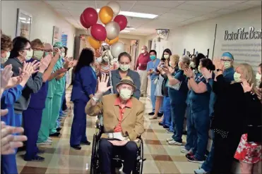  ?? Jeremy Stewart ?? Redmond Regional Medical Center and Harbin Clinic doctors, nurses and staff applaud as Ted Thomas is helped down a hallway Friday after being discharged from inpatient rehab. The 83-year-old was one of the hospital’s first patients that tested positive for COVID-19 and made a full recovery.