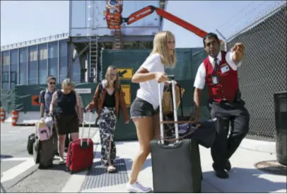  ?? KATHY WILLENS — THE ASSOCIATED PRESS ?? In this Wednesday photo, a Port Authority customer care representa­tive helps arriving passenger Katie Smith, of Chicago, find a temporary taxi pickup location outside of Terminal B at LaGuardia