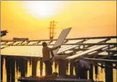  ?? FU JIANBIN / FOR CHINA DAILY ?? Workers install solar panels at a photovolta­ic power station in Changxian county, Jiangxi province, in April. The area below the panels also serves as a fish farm, increasing the efficient use of space and generating more income.