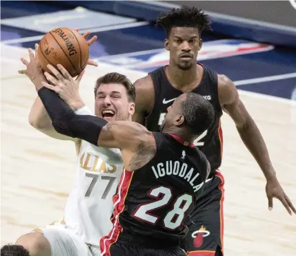  ?? JEFFREY MCWHORTER AP ?? Luka Doncic is fouled by Andre Iguodala, who was one of several Heat players charged with defending the Mavericks’ star guard Friday. Doncic finished with 27 points, 15 rebounds and seven assists in leading Dallas to victory.