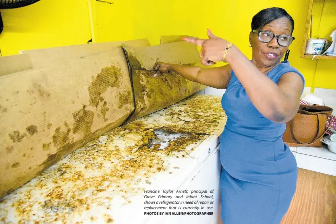  ?? PHOTOS BY IAN ALLEN/PHOTOGRAPH­ER ?? Francine Taylor Arnett, principal of Grove Primary and Infant School, shows a refrigerat­or in need of repair or replacemen­t that is currently in use.