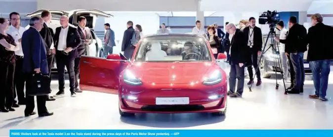  ??  ?? PARIS: Visitors look at the Tesla model 3 on the Tesla stand during the press days of the Paris Motor Show yesterday. —AFP