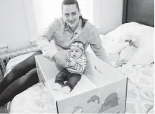  ??  ?? Dolores Peterson and her three-month-old daughter, Ariabella, show their baby box. New Jersey is the first state to send newborns and their parents home with a box that doubles as a crib, with the aim of cutting back on sudden unexpected infant deaths.