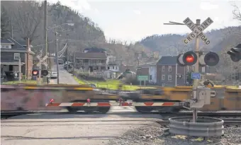  ?? PHOTOS BY JASPER COLT, USA TODAY ?? A train passes through the town of Welch, W. Va. Railroad crossings are one of the many road features that slow area drivers.