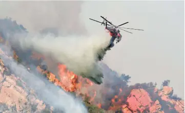  ??  ?? A helicopter drops flame retardant on a wildfire in Malibu. — AFP photo