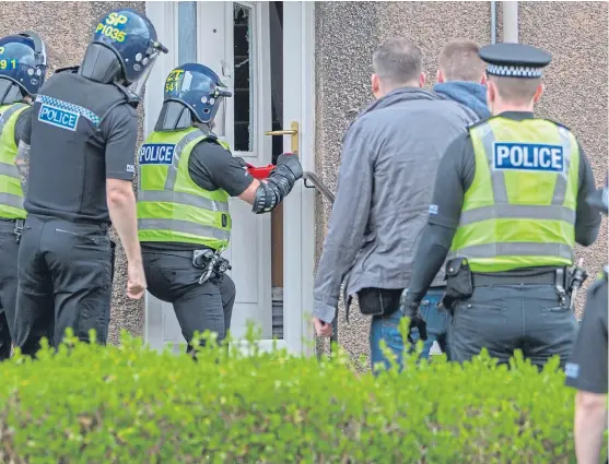  ??  ?? Officers of the community investigat­ion unit force entry to a property in Kirkcaldy during a raid as they search for crack cocaine.