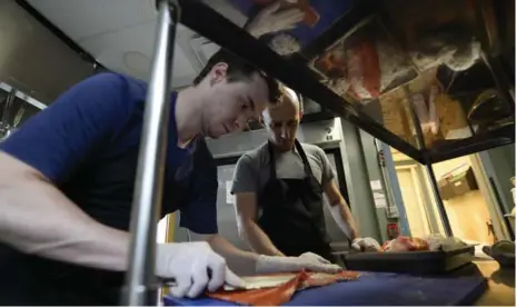  ?? AARON HARRIS FOR THE TORONTO STAR ?? Cook Adam Dalton teaches Corey Mintz how to clean a salmon at Honest Weight, a seafood store and restaurant in Toronto’s Junction neighbourh­ood.