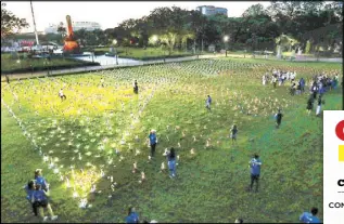  ?? MIGUEL DE GUZMAN ?? Volunteers, including frontliner­s from the Philippine General Hospital, help arrange an estimated 3,000 Liter of Light solar lamps to form the Philippine flag (inset) in Rizal Park in Manila the other night. Participan­ts also tied to the lamps hospital bands bearing the names of fallen colleagues.