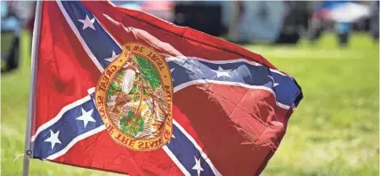  ?? CAITLYN JORDAN/NAPLES DAILY NEWS ?? A Confederat­e flag with an upside down Florida state seal is flown at the 2022 Patriot Fest on March 19, 2022, at Sugden Regional Park in Naples.