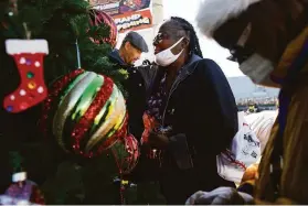  ?? Jessica Christian / The Chronicle ?? Juanita Jackson (center) and Mary Fleming work alongside volunteers to decorate a tree donated by Wells Fargo in the Bayview district last week.