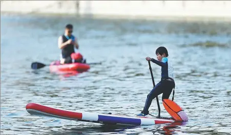  ?? WEI XIAOHAO / CHINA DAILY ?? A child tries out paddleboar­ding on a river in Beijing in May.