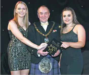  ??  ?? Provost Ian Clarkson presents the trophy to Megan McNicol and Ellie Wood of Arran Active Schools young leaders.