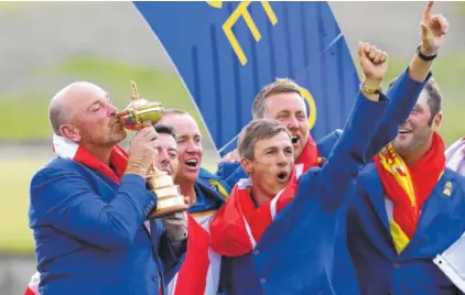  ?? AP PHOTO/ALASTAIR GRANT ?? Europe team captain Thomas Bjorn kisses the Ryder Cup as he celebrates with his golfers after Sunday’s win over the U.S. team at Le Golf National, near Paris. Europe won 17 1/2-10 1/2.