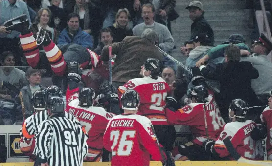  ?? POSTMEDIA FILES ?? During a game in November 1996, the Flames’ Sasha Lakovic, with feet up in air, went into the Edmonton crowd after a fan poured a beer on Calgary coach Guy Lapointe.