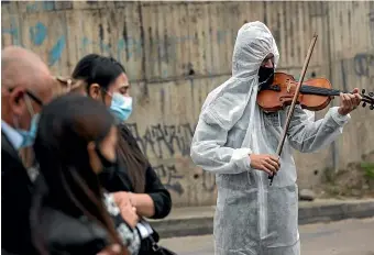  ?? AP ?? A violinist plays for the relatives of a Covid-19 victim during her funeral in Bogota, Colombia yesterday. Colombia is experienci­ng a surge in deaths from Covid-19.