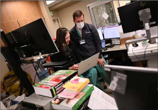  ?? HELEN H. RICHARDSON — THE DENVER POST ?? Pharmacy supervisor Gabrielle Jacknin, left, and clinical pharmacist Andrew Kluemper work together on their computers at their work station in the emergency department at Uchealth University of Colorado Hospital in Aurora on March 13.