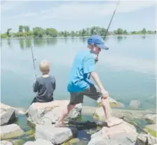  ?? Daily Camera file ?? Will Luckenbill walks across rocks to a different spot while Bennett Ross continues to fish during the 2015 fishing derby at Waneka Lake Park in Lafayette.