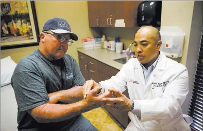  ?? Erik Verduzco ?? Las Vegas Review-journal @Erik_verduzco Dr. Richard Baynosa, right, chief of plastic surgery at University Medical Center and the UNLV School of Medicine, checks Ben Mays’ thumb Tuesday at the School of Medicine. Mays, whose thumb was nearly severed...