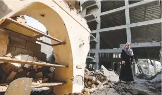  ??  ?? A PALESTINIA­N WOMAN walks through rubble in the damaged Arts and Crafts Village, beside a building that was hit by Israeli air strikes the day before, in Gaza City in this July 15 photo. Israel’s military said it had launched air strikes targeting...