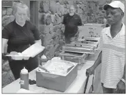  ?? / Spencer Lahr ?? Johnny Mitchell’s Smokehouse employee Kaitlyn Turner serves up a barbecue plate for Fairview School alumnus Leo Word, while chef Johnny Mitchell looks on during the eighth annual barbecue sale at the Rome Civic Center to benefit restoratio­n efforts of...