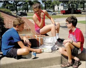  ?? Janelle Jessen/Herald-Leader ?? Wilson Cunningham, Faith Ellis and Elliot Posey checked their solar oven to see how well it baked chocolate chip cookie dough during Scholar’s Science Academy at John Brown University on Thursday. Elementary and middle-school students spent the week...