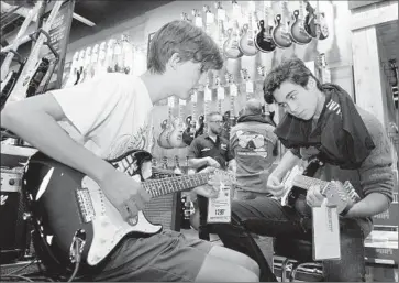  ?? Photog raphs by Mariah Tauger For The Times ?? JACK WOODS, left, and Nate Aldin have a little jam session during the grand opening of Guitar Center’s Westlake Village store. The retailer is famous for allowing customers to endlessly fiddle with its products.