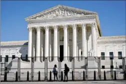  ??  ?? People view the Supreme Court from behind security fencing Sunday in Washington, D.C., after portions of an outer perimeter of fencing were removed overnight to allow public access. (AP Photo/Patrick Semansky)