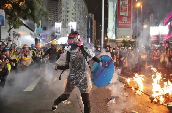  ?? Photo: AP ?? A protester throws a smoking tear gas shell back at Police officers in Hong Kong on August 31, 2019.