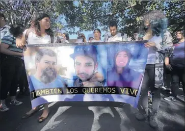  ?? Carlos Zepeda EPA/Shuttersto­ck ?? YOUTHS hold a banner depicting film students Javier Salomon Aceves, left, Marco Avalos and Daniel Diaz.