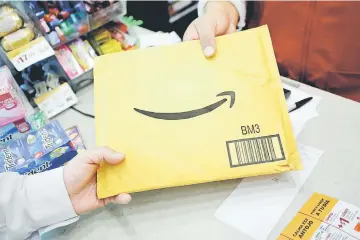  ?? — Reuters photo ?? A customer picks up an Amazon package at a Femsa’s Oxxo convenienc­e store in Monterrey, Mexico.