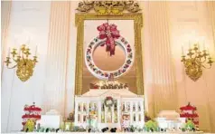  ??  ?? Above, this year’s White House gingerbrea­d house in the State Dining Room features 150 pounds of gingerbrea­d covered by 100 pounds of bread dough to form the white exterior. At left, first lady Michelle Obama speaks to military families while providing...