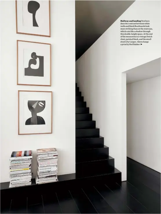  ??  ?? Hallway and landing Nowhere does the contrast between white walls and black floorboard­s look more striking than on the staircase, which cuts like a shadow through this double-height space. At the end of the mezzanine is a vintage Dutch chair, painted black, and the small stool is by Liaigre. Above hangs a print by Stef Bakker