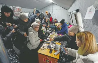  ?? REUTERS ?? La gente carga sus dispositiv­os en un punto de calefacció­n del gobierno en Kiev