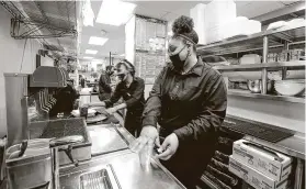  ?? Steve Gonzales / Staff photograph­er ?? Misty Martin prepares a drink for a customer at Peli Peli in the Galleria. The restaurant has shifted its business model toward takeout and delivery to survive.