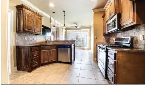  ?? ?? The kitchen supplies tile flooring, granite countertop­s, a breakfast bar and stainless-steel appliances.