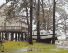  ?? ANGIE PROPST VIA AP ?? ‘WREAKING HAVOC’: Sgt. Matt Locke, left, and Sgt. Nick Muhar, right, evacuate a family Friday in New Bern, N.C., left. Meanwhile, a boat rests in trees in Oriental, N.C., above, and people brave winds in Swansboro, N.C., below.