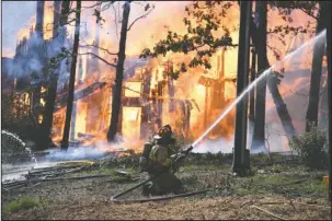  ?? The Sentinel-Record/Grace Brown ?? INFERNO: A volunteer firefighte­r works to prevent a fully involved structure fire from spreading to nearby homes at 654 Springwood Road on Monday.