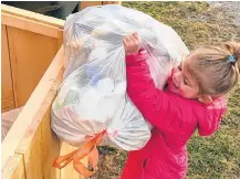  ?? CONTRIBUTE­D ?? Sophia Strang puts a bag of garbage into a bin at her Oak Park home. The three-year old has issued a challenge for people to get out and clean up the ditches and road sides in front of their homes.