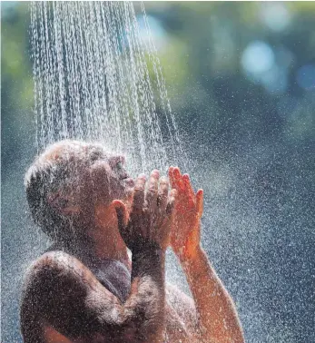  ?? FOTO: DARKO VOJINOVIC/DPA ?? Vielleicht, wie dieser Mann auf unserem Symbolbild, einfach eine kalte Dusche an heißen Tagen nehmen, wenn kein Pool vorhanden oder ein Besuch am See nicht möglich ist.