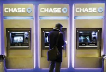  ?? THE ASSOCIATED PRESS ?? A customer uses an ATM at a branch of Chase Bank, in New York. Fewer Americans are without access to a checking or savings account, according to a survey released Thursday by federal regulators, a sign that the improving economy is helping lift the...