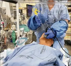  ?? CONTRIBUTE­D BY EMORY UNIVERSITY ?? Dr. Cinnamon Sullivan and her colleague Dr. Jeremy Collins demonstrat­e how the box can be used to help perform procedures such as intubating a patient while creating a protective barrier for health care workers.