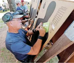  ??  ?? Mike Dowd, a state park ranger from Pueblo, Colorado, scores a fellow officer Friday in the Dale DeBerry Memorial Regional and State Police Pistol Combat Championsh­ips.